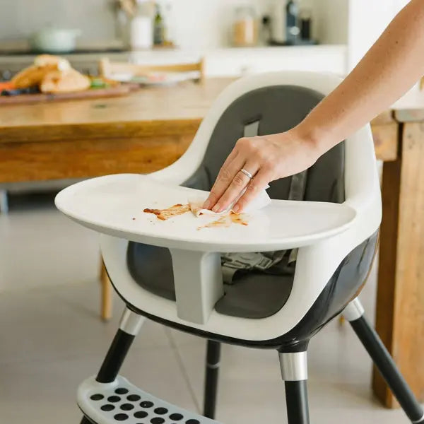 Woman cleaning high chair with non-toxic cleaning wipe