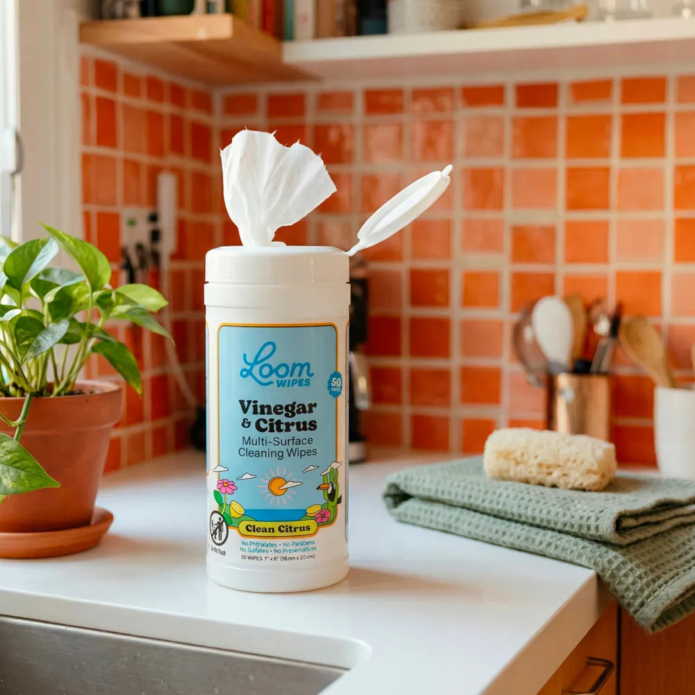 Loom Wipes vinegar and citrus cleaner container on a kitchen counter with a tiled backsplash